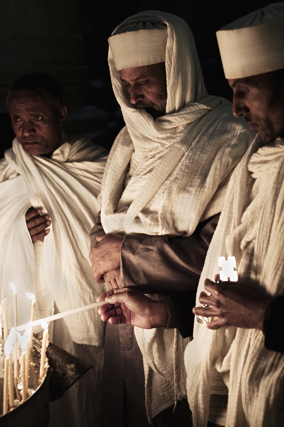 Photography of Ethiopian Christian pilgrims lighting candles at the Holy Sepulchre church in Jerusalem